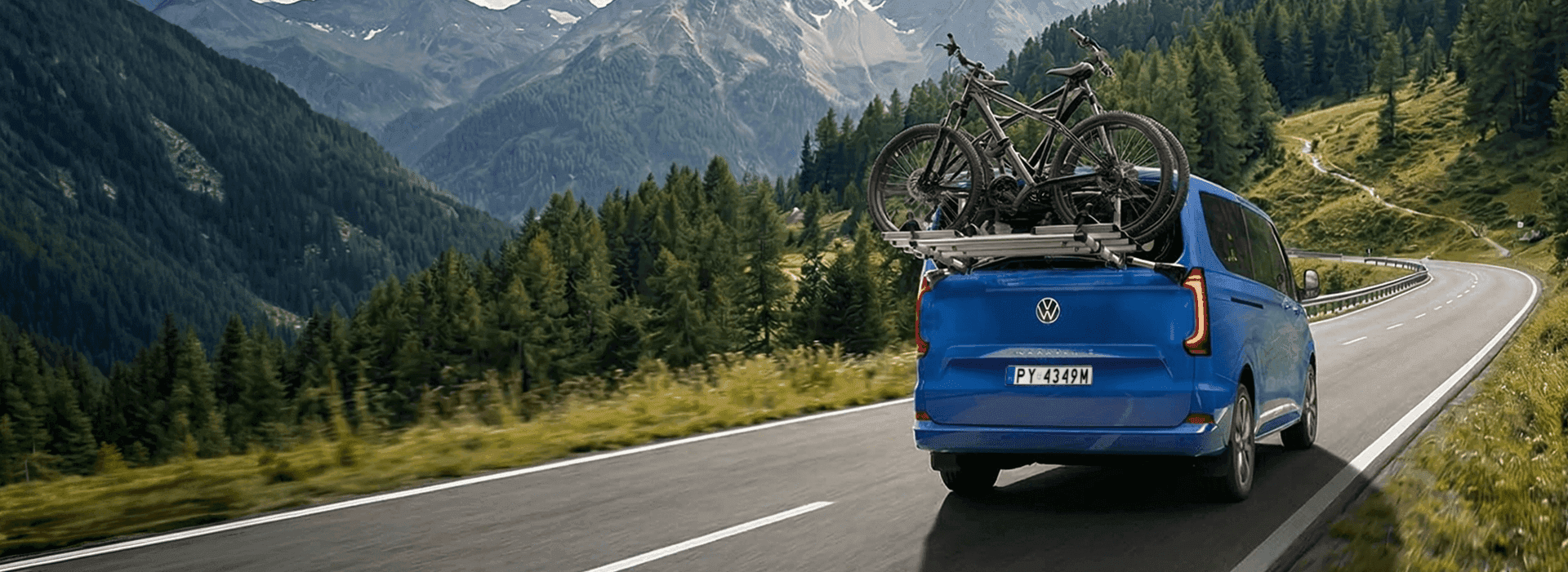 Kobieta z rowerem na leśnej drodze, obok samochodu.