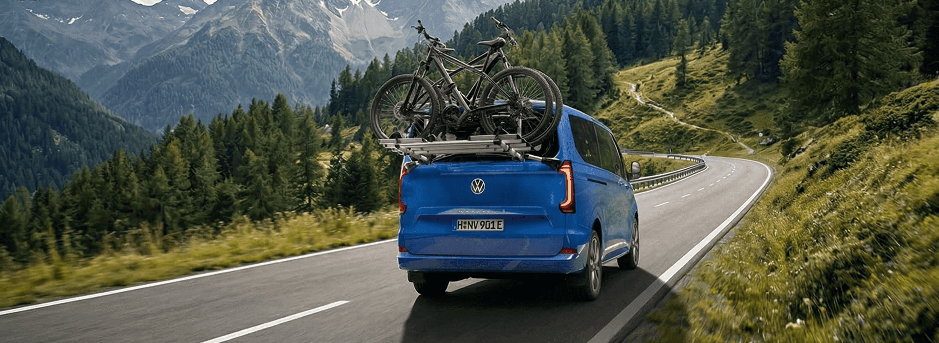 Kobieta z rowerem na leśnej drodze, obok samochodu.